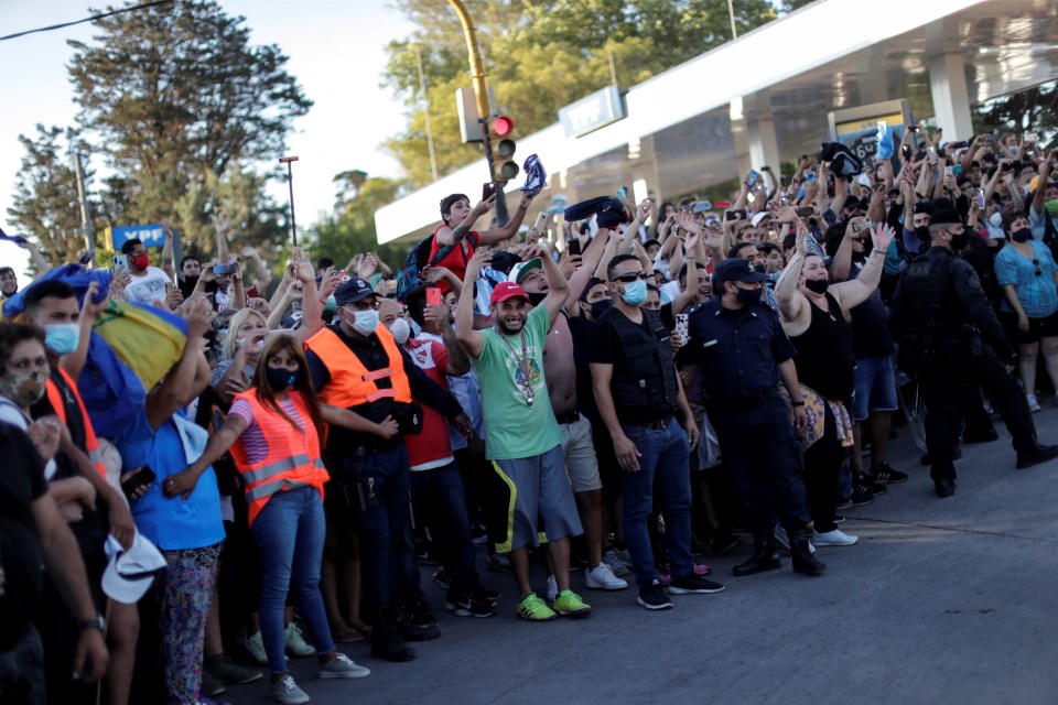 Mourners wave at the hearse carrying Maradona’s body drives past