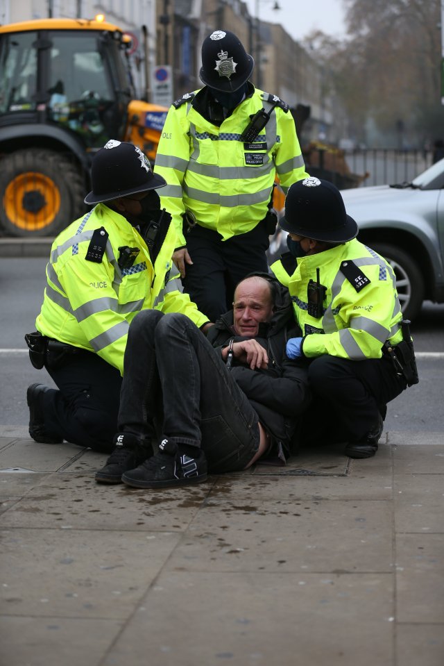 Police put an anti-lockdown protester in handcuffs in central London