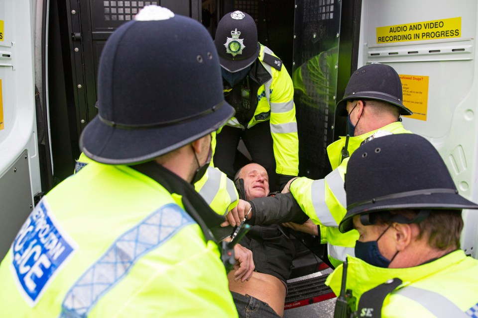 An anti-lockdown protester gets put into a van by police