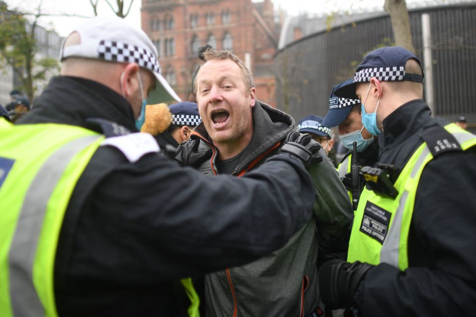 Police put an anti-lockdown protester in handcuffs during demonstrations