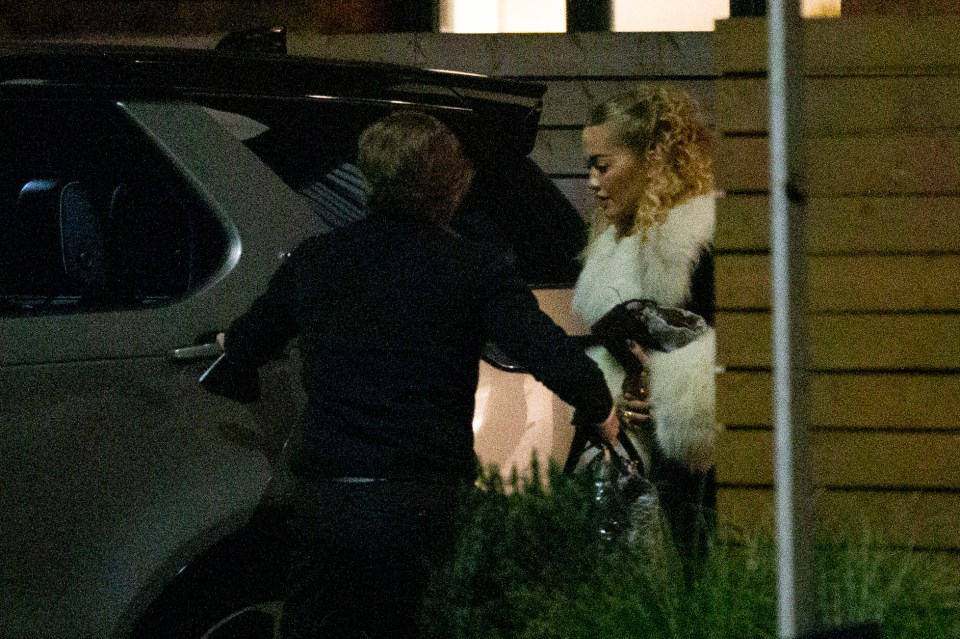 Rita was seen in high heels, a white satin dress and a coat