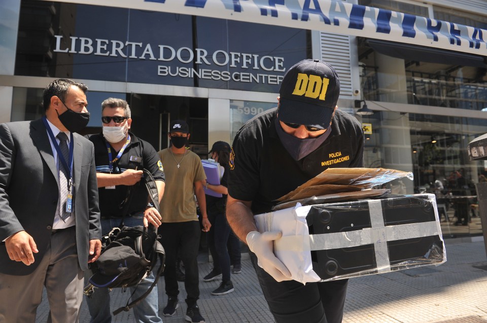 Police officers leave the doctor’s office with a computer and some documents following a raid today