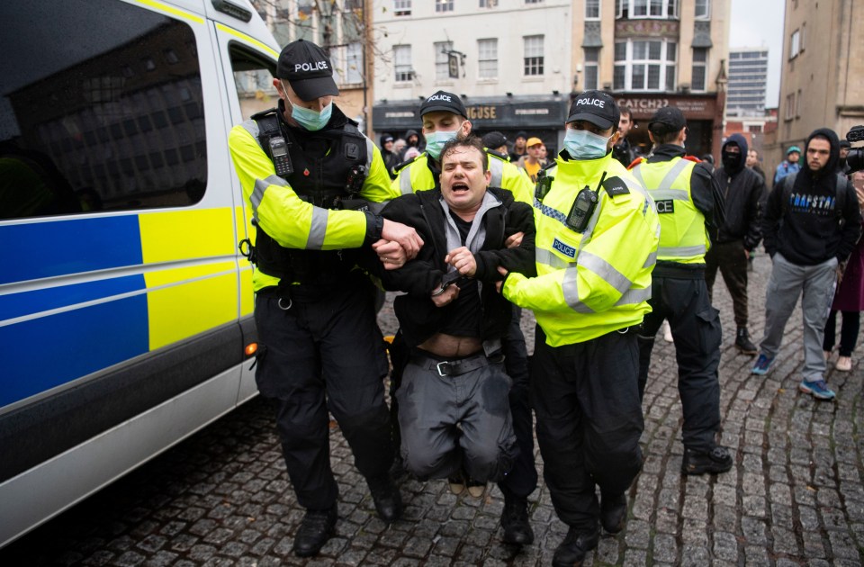 Cops wearing masks carry away a man from the march