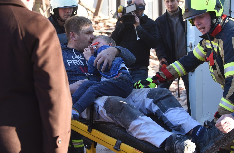 A man holding a child is carried on a stretcher