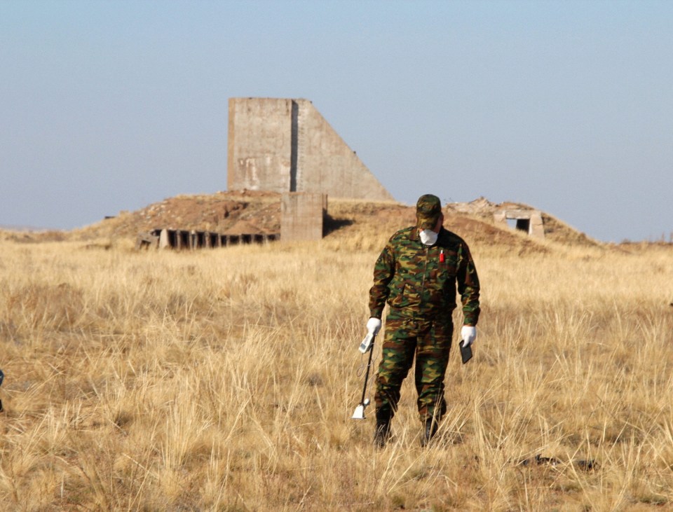 A man measures radiation levels in an area more than 1 kilometer from the hypocenter of the test site