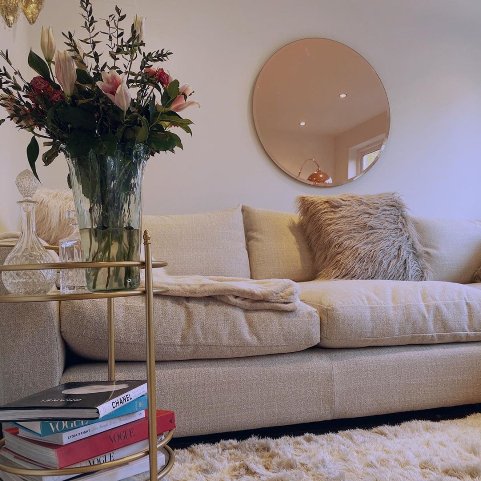 The lounge room is decorated with neutral furnishings and large round golden-edged mirror