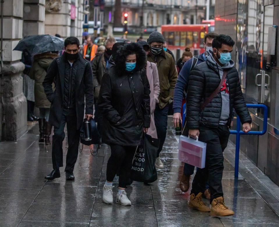 Commuters wearing masks brave the cold and rain in Westminster, London