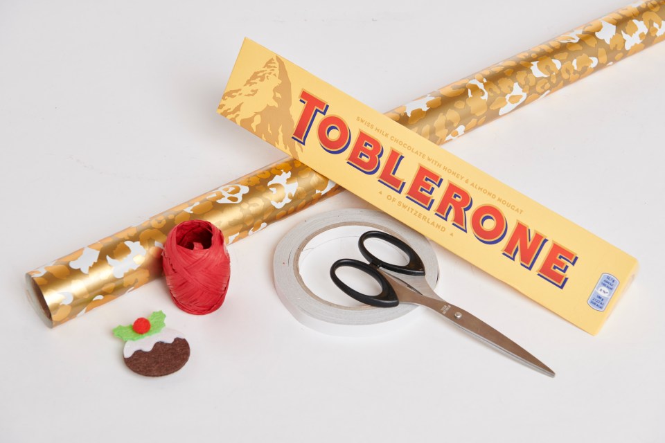 Lay the Toblerone on the paper and rotate three times to give you the correct amount of paper