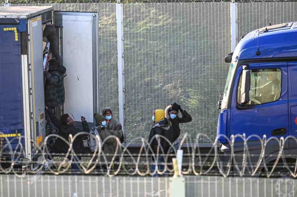 Migrants were seen trying to board lorries as they waited to board shuttles at the Eurotunnel entrance in Calais today