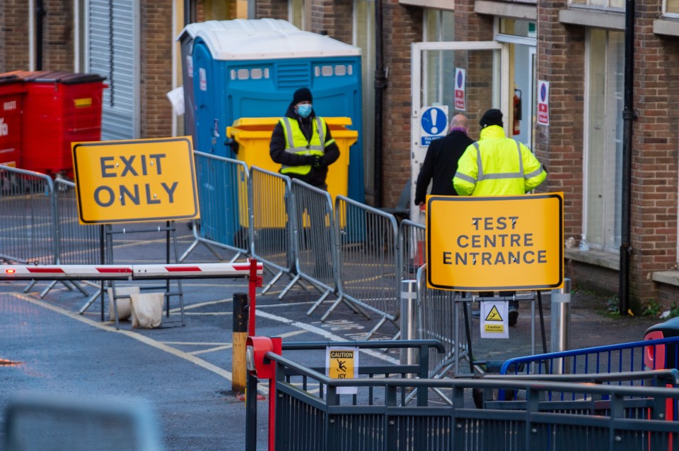 A couple are guided by a security guard as they enter a Covid-19 testing centre in High Wycombe