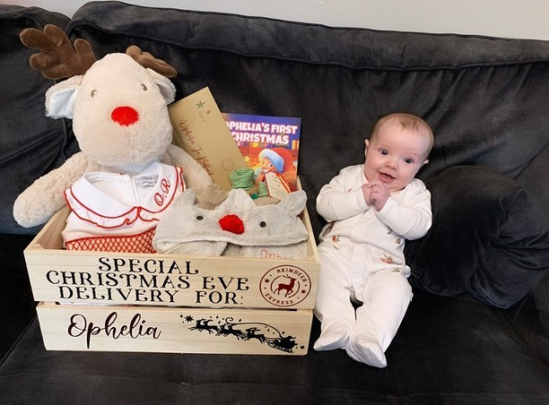 Ophelia smiles next to her personalised Christmas Eve box jam-packed with goodies