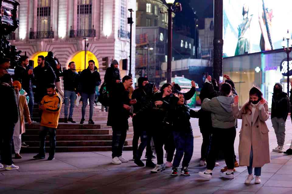 Groups of people gather together at Piccadilly Circus