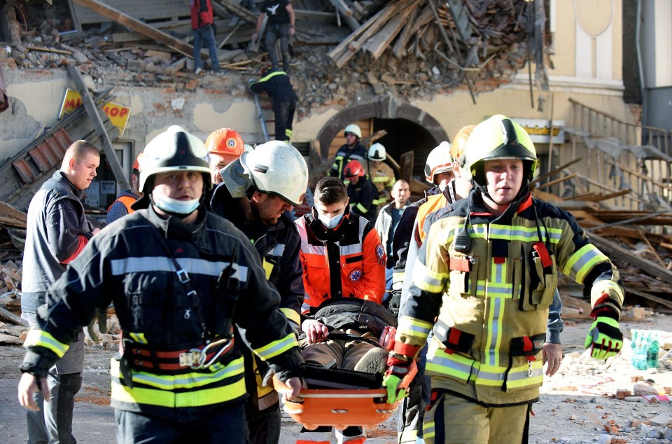 A person is carried away from a collapsed building on a stretcher