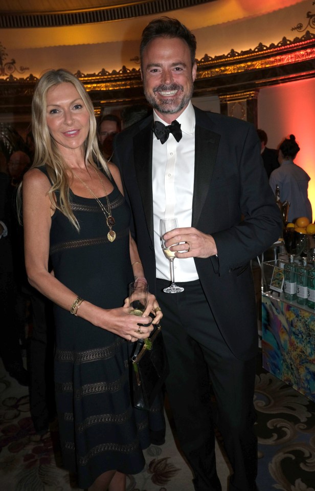 a man in a tuxedo and a woman in a black dress pose for a photo