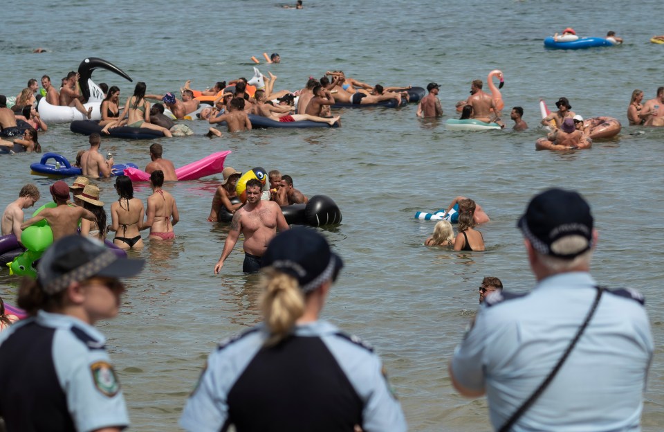 Police watch on as a large crowd gathers to enjoy the soaring temperatures