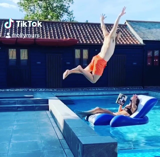 Olly leaps into his swimming pool as his girlfriend lounges on an inflatable