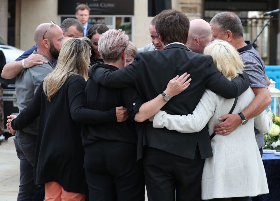 Family members of the three victims comfort each other after lighting candles during a vigil at Market Place, Reading