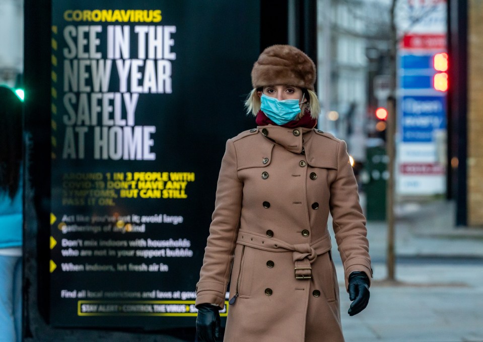 A woman walks past a sign urging Brits to see in the New Year at home