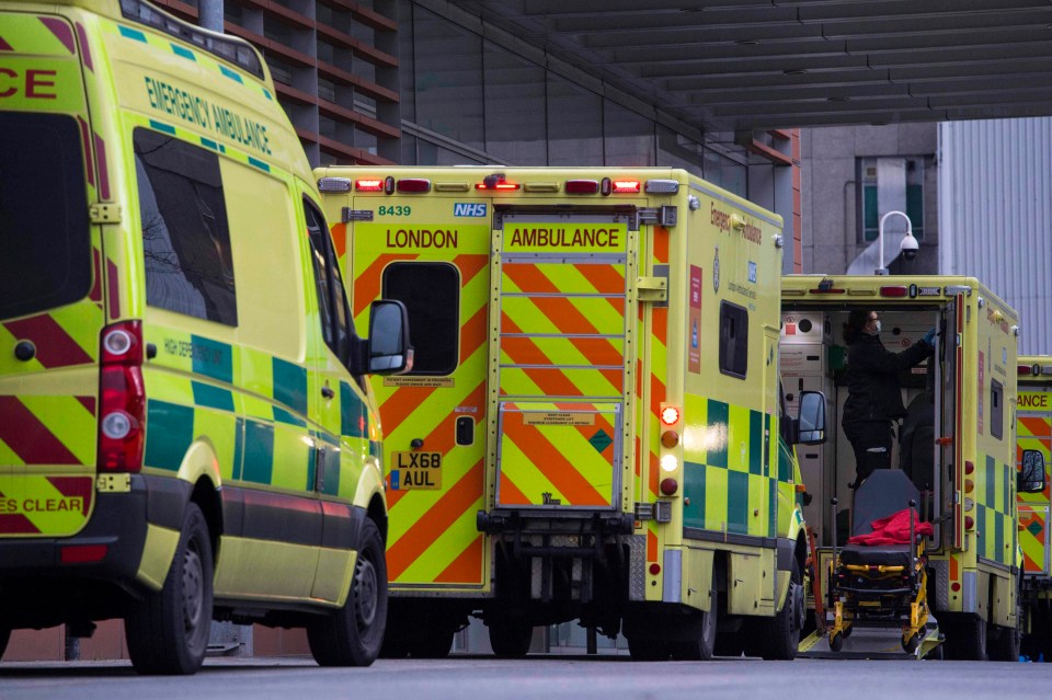 A hospital worker disinfects one of the ambulances lined up at the Royal London Hospital in East London on Sunday