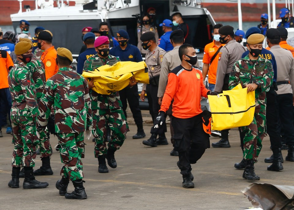 Rescuers carrying body bags 