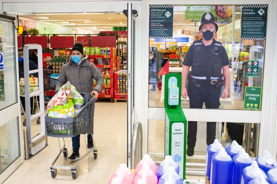 A shopper passes a police cut-out at a Morrisons in South London