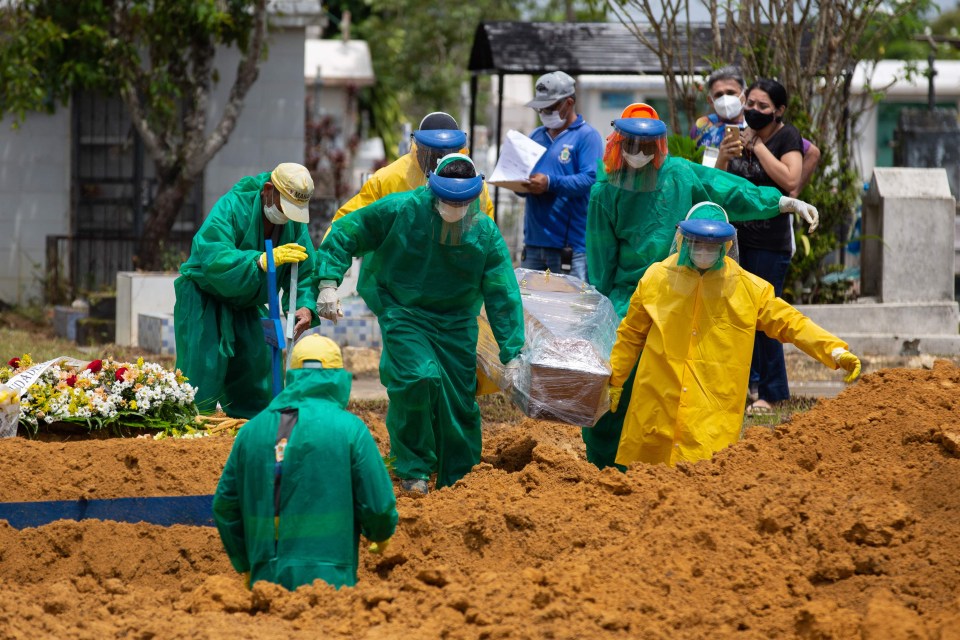 Gravediggers bury a Covid-19 victim while surrounded by relatives at the Nossa Senhora Aparecida cemetery in Manaus on January 13