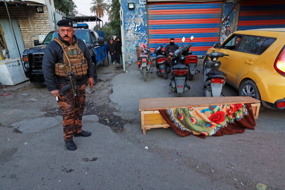 A member of the security force stands next to a victims coffin