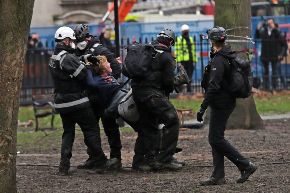 A protester is seen being taken from the scene this morning