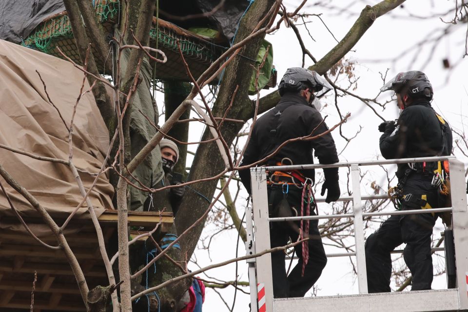 An activist is seen speaking to men on a cherry picker