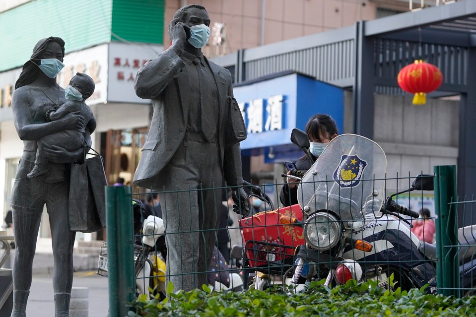 Statues along a street in Wuhan are seen with masks placed on them