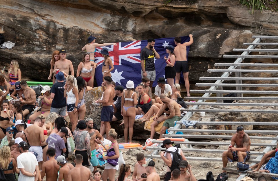 Beachgoers pin up an Australia flag to the rocks on Gordons Bay