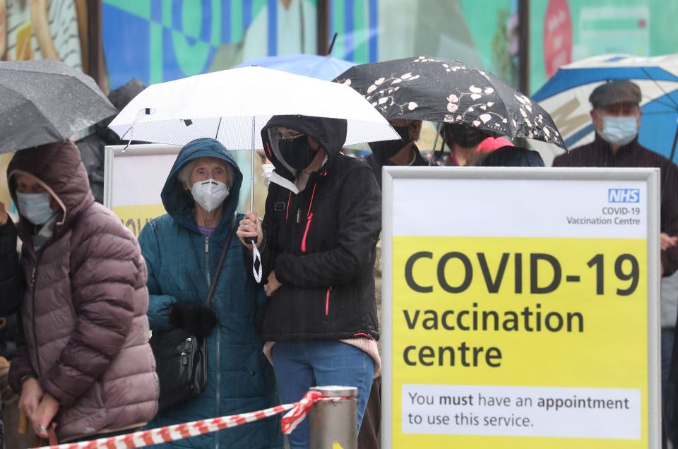 People queue in bad weather to enter a Covid-19 vaccination centre in Folkestone, Kent