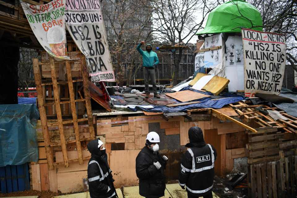 An activist raises his fist as enforcement agents monitor the camp