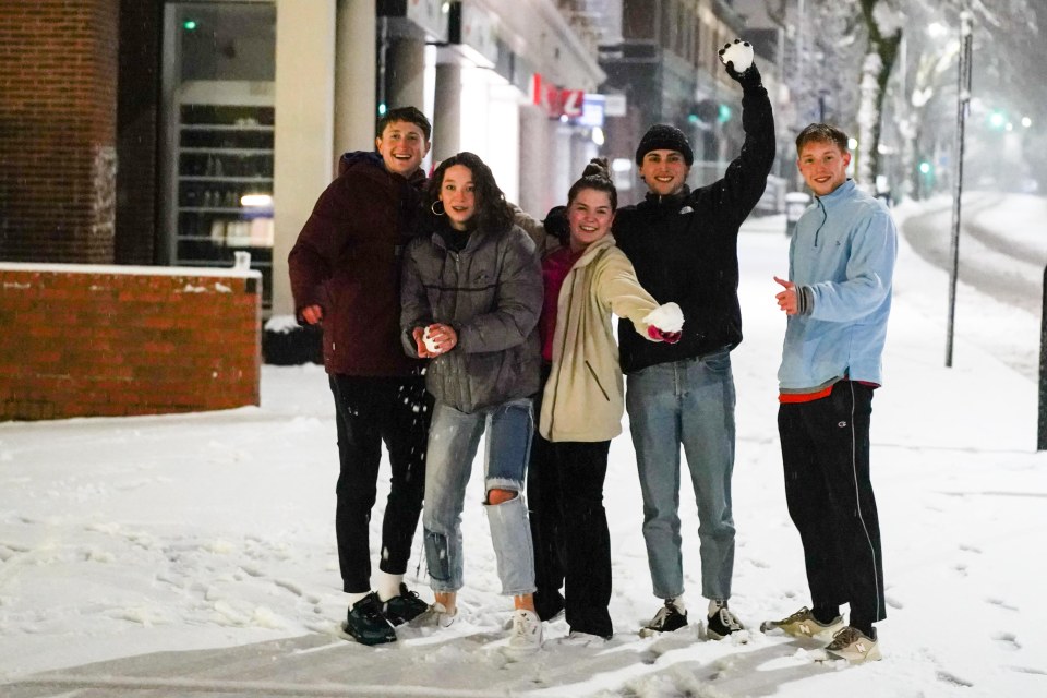 Students pose for a photograph as they play in the snow in Sheffield