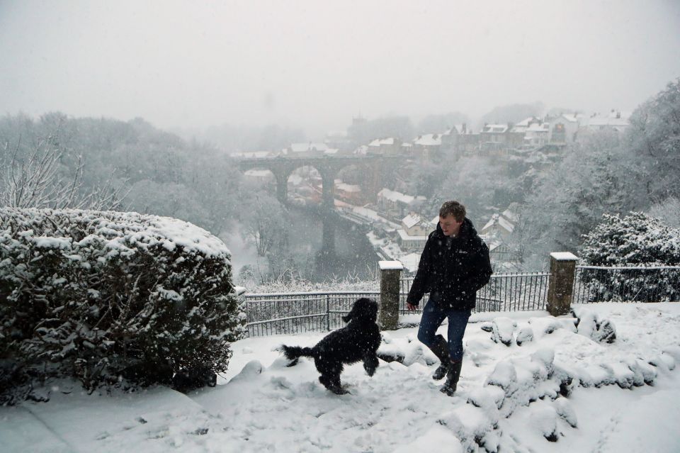 A man walks a dog in Knaresborough in North Yorkshire after snow fell overnight