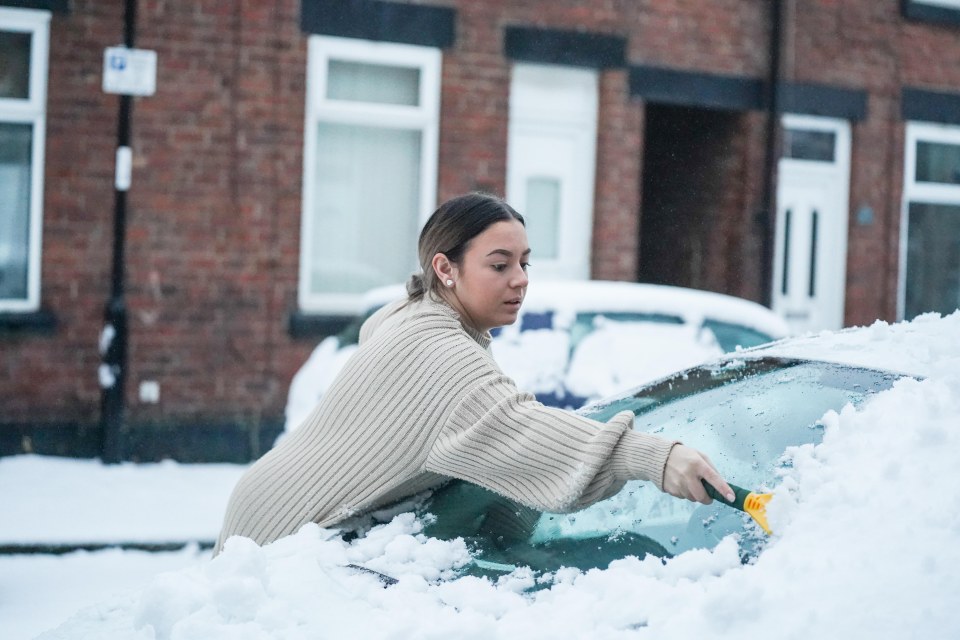 A woman clears snow from her car in Sheffield this morning