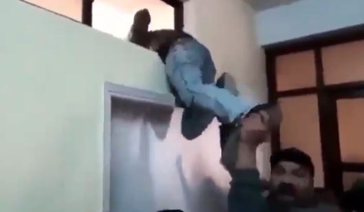 A man tries to climb through a window as a mob hunts for the Christian nurse accused of blasphemy