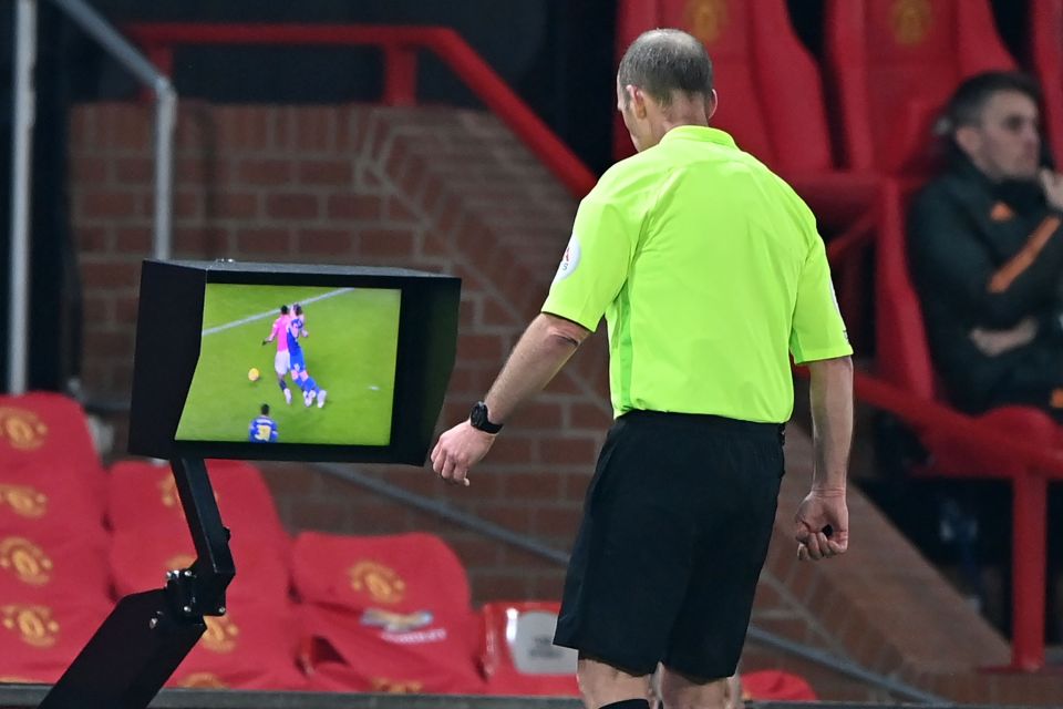 Ref Mike Dean watches replays before confirming Man Utd's penalty and handing a red card to Jan Bednarek