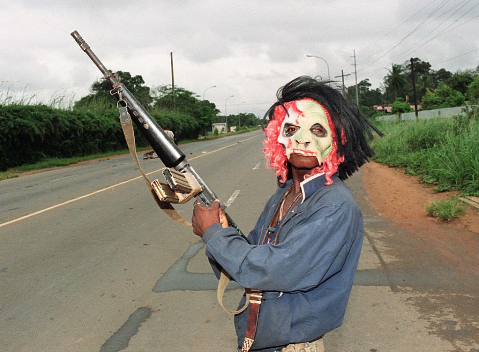 A masked rebel holding a machine-gun patrol in Monrovia in 1990