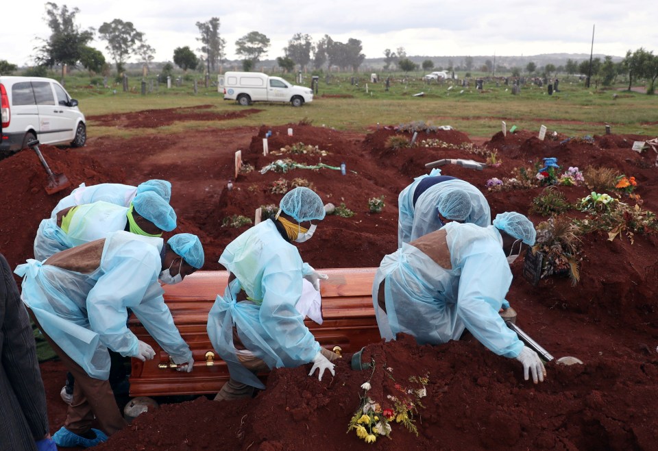 Funeral workers carry a casket during the burial of a Covid victim in Johannesburg