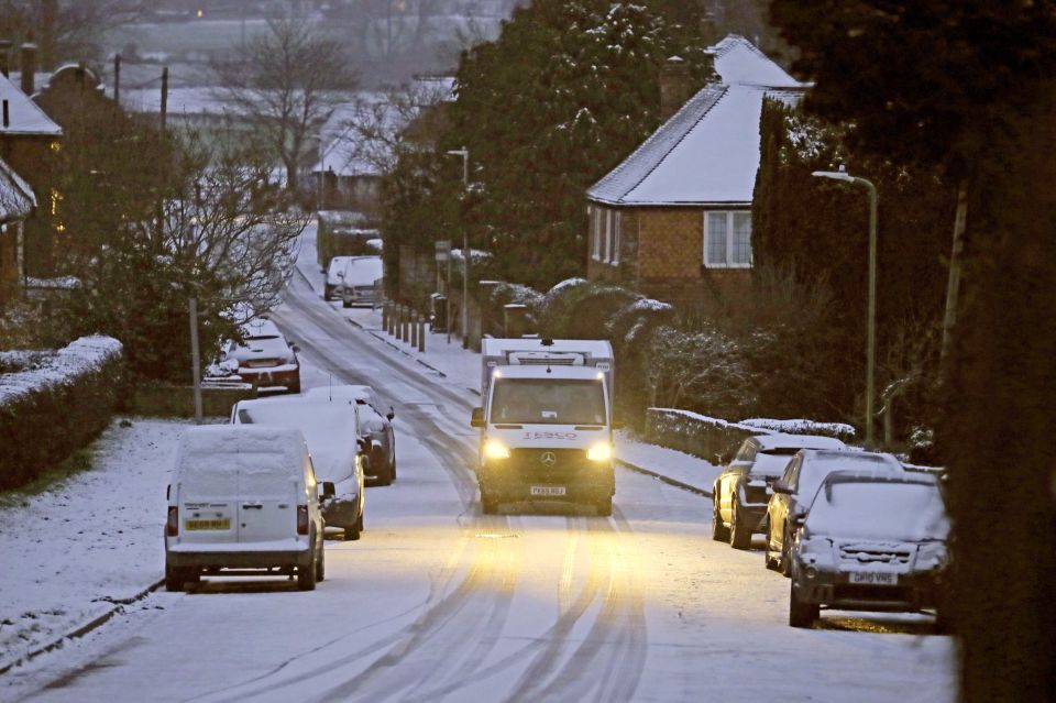 A Tesco delivery van makes its way along a road covered in snow near Ashford in Kent this morning