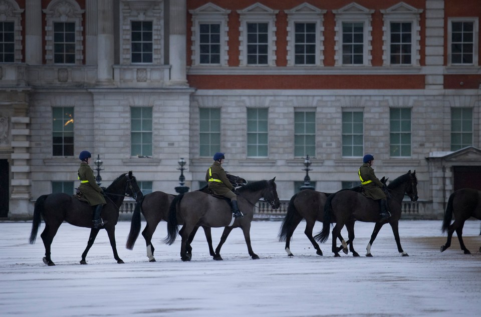 Members of The Blues and Royals exercise their horses on a snowy Horse Guards parade in central London just before dawn