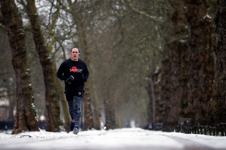 A man jogs in snow-covered St James's Park, London