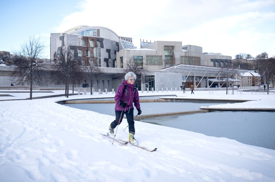 A woman skis through the snow in the grounds of the Scottish Parliament in Edinburgh