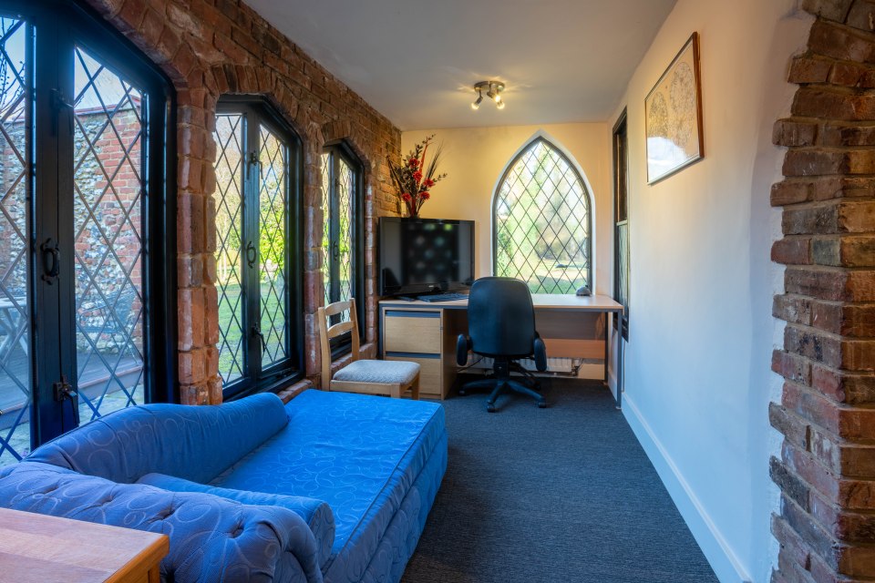 The home has a cosy study with a sofa and large windows