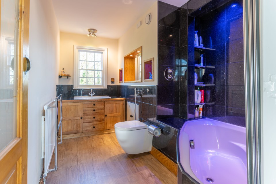 This is one of the two bathrooms in the home as this one has a large bathub with neon lighting