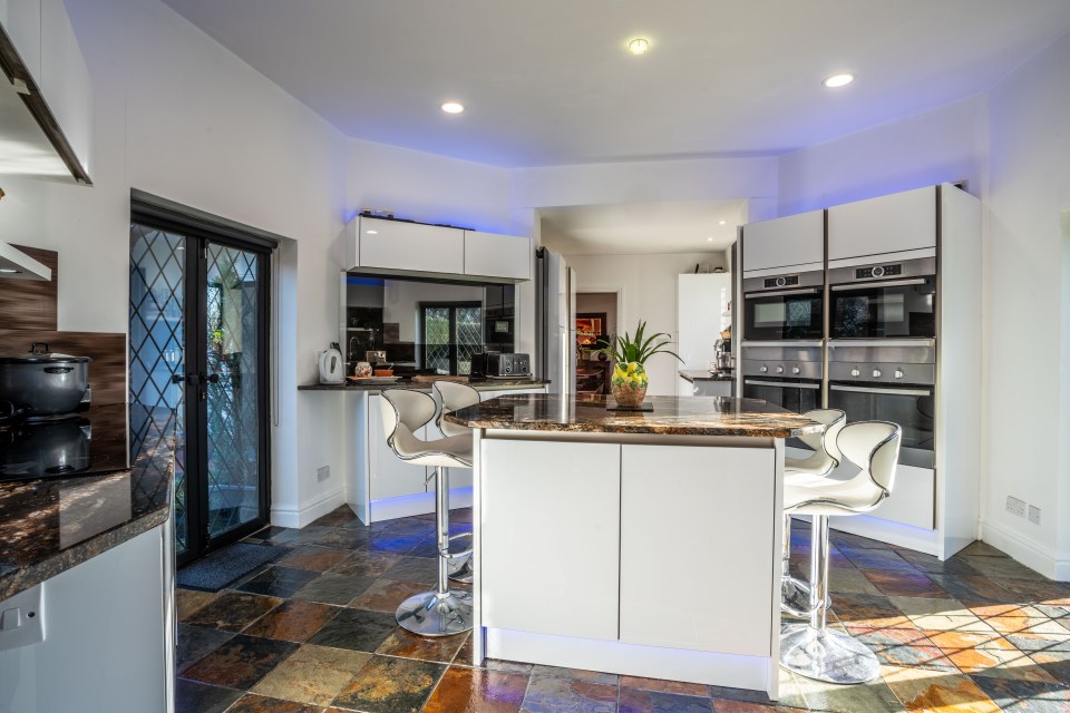 The kitchen has a sleek breakfast bar with two ovens and two microwaves