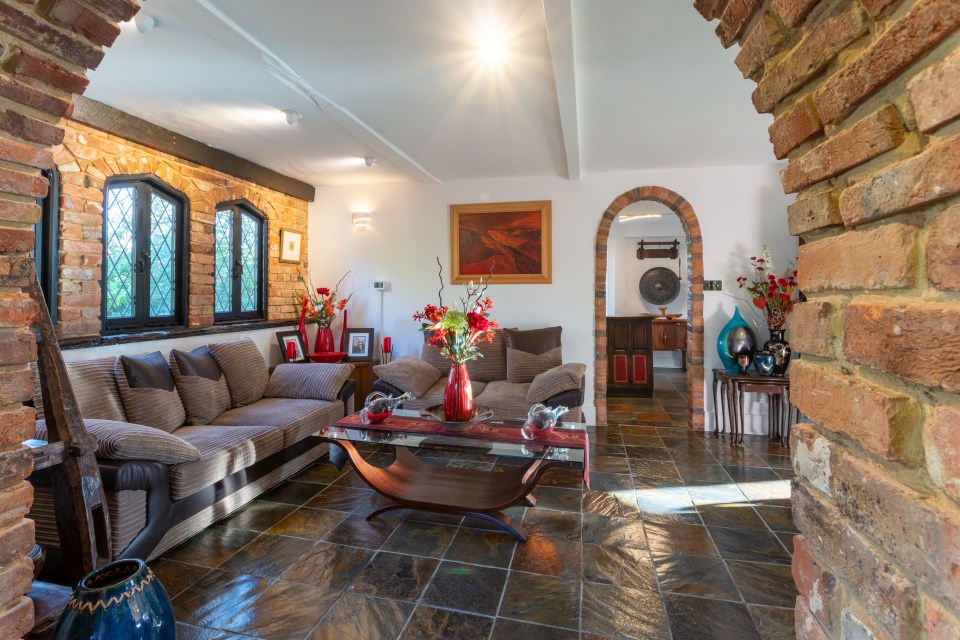 This living room has polished brown tiles on the floor with brick walls