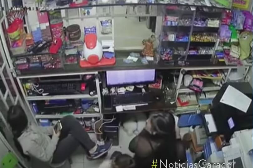 The hero teenager, left, is seen behind the counter with her mother and two-year-old sister as the robbers burst in