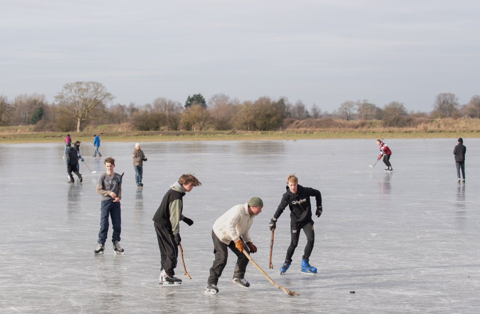 People play ice hockey on frozen flooded fields near Ely in Cambridgeshire